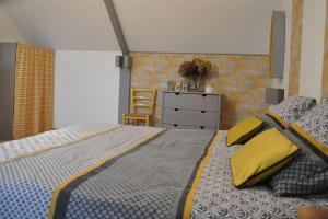 ein Schlafzimmer mit einem Bett mit gelben Kissen und einer Kommode in der Unterkunft Les Hortensias in Gatteville-le-Phare