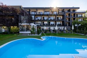 a hotel with a large swimming pool in front of a building at Hotel Finkenhof - Feel at home in Schenna