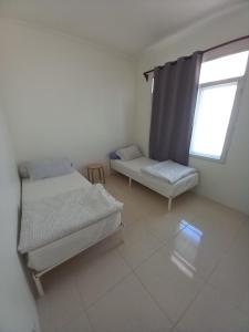 Cette petite chambre comprend 2 lits et une fenêtre. dans l'établissement Shambala palm beach anyer, à Anyer