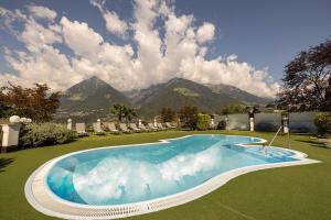 a large swimming pool with mountains in the background at Hotel Finkenhof - Feel at home in Schenna