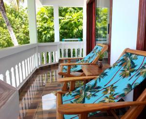 a porch with chairs and tables and windows at MT Seaside Apartment in La Digue