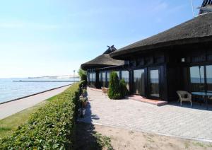 ein Haus am Wasser mit einem Tisch und Stühlen in der Unterkunft Apartamentai Ešerinėje in Neringa