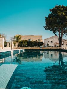 una grande piscina con un albero sullo sfondo di Masseria Gagliardi a Taranto