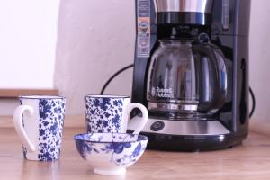 drei blaue und weiße Tassen und eine Kaffeemaschine in der Unterkunft Studio la maison bleue in Cotignac
