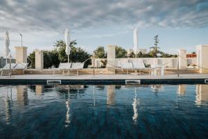 une piscine d'eau avec des chaises et une fontaine dans l'établissement Masseria Gagliardi, à Tarente
