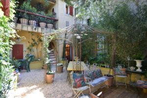 um pátio com uma mesa e cadeiras num jardim em La BARBELLA em Lourmarin