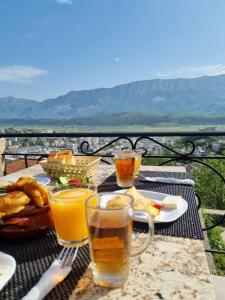 Guesthouse Mele في غيروكاستر: طاولة مع الطعام وكأسين من البيرة