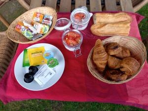 ein Picknick mit Körben mit Essen und Brot auf einer roten Decke in der Unterkunft Cabane suspendue dans les arbres in Villebon-sur-Yvette