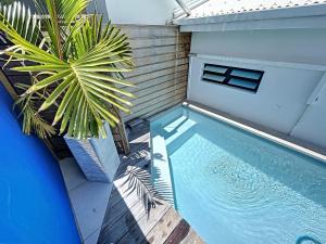 a swimming pool with a palm tree next to a house at DEEP BLUE Vue mer Piscine privative 2 chambres in Le Gosier