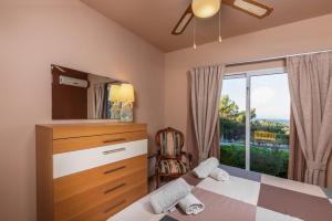 a bedroom with a bed and a dresser and a window at Villa René in Koskinou