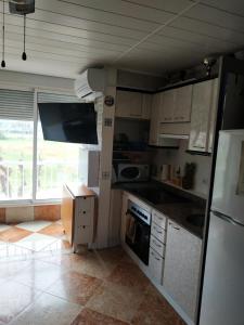 eine Küche mit weißen Schränken und einem großen Fenster in der Unterkunft apartamento en la pineda in La Pineda