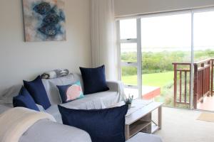 a living room with a couch and a large window at W8 - Goose Valley Golf Estate in Plettenberg Bay