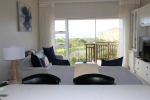 a living room with a couch and a large window at W8 - Goose Valley Golf Estate in Plettenberg Bay