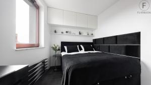 a bedroom with a black bed and a window at Flatbook Apartments Waterlane Island SPA with Riverview in Gdańsk