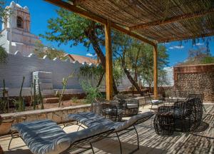 een patio met stoelen en tafels en een pergola bij Terrantai Lodge in San Pedro de Atacama