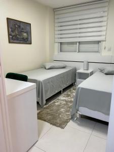um quarto branco com 2 camas e uma janela em Apartamento Vida Boa em Gravatal