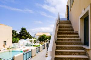 a staircase leading up to a building with a swimming pool at Hotel Baglio Di Scopello in Scopello