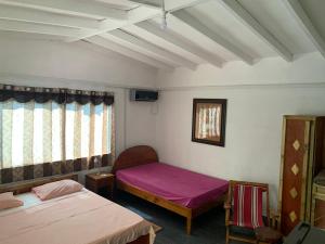 a small room with two beds and a window at Villa Manoir in Anse Lazio