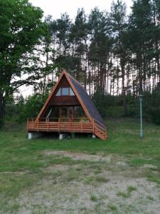 a small cabin with a gambrel roof in a field at Domki pod Dębami in Trzcianka