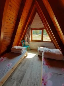 a attic room with two beds and a window at Domki pod Dębami in Trzcianka
