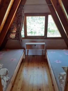 two beds in a room with a window and a desk at Domki pod Dębami in Trzcianka +3 photos