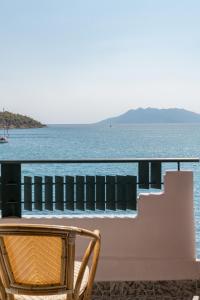 a chair sitting on a balcony overlooking the water at Binji Hotel in Ancient Epidavros
