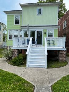 una casa con una cubierta blanca y escaleras en Key Lime Cottage steps from Cape Charles Beach, en Cape Charles