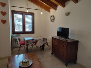 ein Wohnzimmer mit einem Tisch und einem TV auf einer Kommode in der Unterkunft Cagliari Elmas Airport Beautiful Mansarda in Assemini
