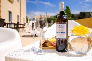 a bottle of wine sitting on a table with two wine glasses at Hotel Baglio Di Scopello in Scopello