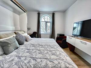 Un dormitorio con una cama y un televisor de pantalla plana. en Auberge Le St-Alexis, en La Baie
