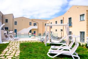 a yard with chairs and a swimming pool at Hotel Baglio Di Scopello in Scopello