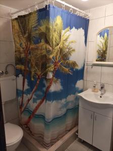 a bathroom with a shower curtain with palm trees at Planinska kuća Bukulja in Arandjelovac