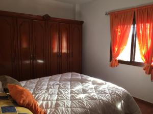 a bedroom with a bed and a window with red curtains at Casa campo Ramos in Cártama