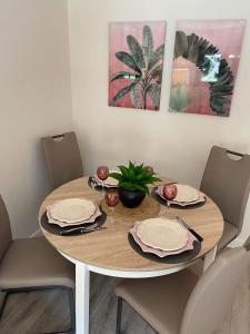 a dining room table with plates and a plant on it at GITE L'Orée Deauvillaise 5 minutes DeauvilleTrouville in Bonneville-sur-Touques