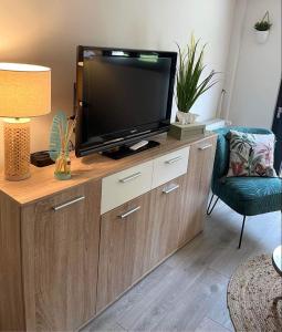 a living room with a television on a wooden entertainment center at GITE L'Orée Deauvillaise 5 minutes DeauvilleTrouville in Bonneville-sur-Touques