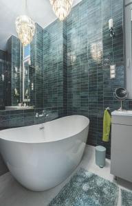 a bathroom with a tub, sink, mirror and bathtub at Basilica Apartments in Budapest