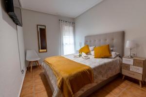 sypialnia z dużym łóżkiem z żółtymi poduszkami w obiekcie Ático con terraza-solárium y piscina 4-6 personas WIFI A/C w mieście Roda +23 zdjęcia