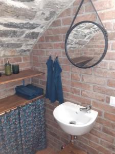 baño con lavabo y espejo en una pared de ladrillo en Cantina antica en Colonno