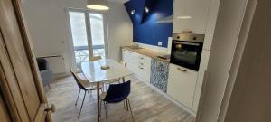 uma cozinha com uma mesa e cadeiras e uma parede azul em Appartement 4 personnes à 100 m de la plage em Berck