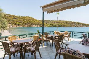 a patio with tables and chairs and a view of the water at Binji Hotel in Ancient Epidauros