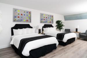 two beds in a hotel room with white and black at Essex House Hotel in Miami Beach