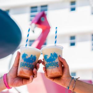 two people holding up drinks in their hands at Essex House Hotel in Miami Beach