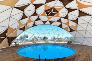 a swimming pool in a building with a geometric ceiling at Reserva Alecrim EcoSuite & Glamping in Santiago do Cacém