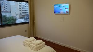 um quarto com toalhas numa cama com uma televisão em Madeira Luxury Amparo Apartment em Funchal