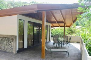 eine Terrasse mit einem Sonnenschirm, einem Tisch und Stühlen in der Unterkunft Casa Danta in Quepos
