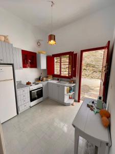 una cocina con armarios rojos y una mesa. en TINA'S HOUSE OUTSTANDING SEASIDE HOUSE Kamares Sifnos, en Kamarai