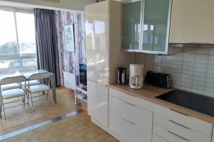 uma cozinha com armários brancos e uma mesa e cadeiras em 39m For 4 Residence With Pool Near Beach em La Grande-Motte