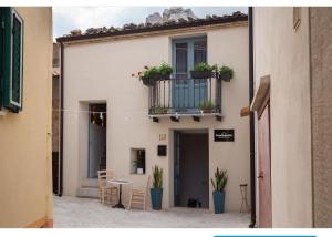 un edificio con un balcón con macetas y una mesa en PORTA SOPRANA luxury guest House & spa, en Sclafani