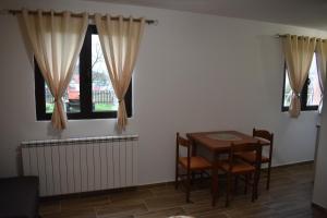 a dining room with a table and chairs and windows at Deluxe Studio & Rooms Zarubica in Žabljak