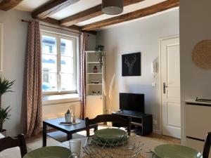 ein Wohnzimmer mit einem Tisch und einem TV in der Unterkunft T2 style cottage - Véranda & Terrasse extérieure in Tours